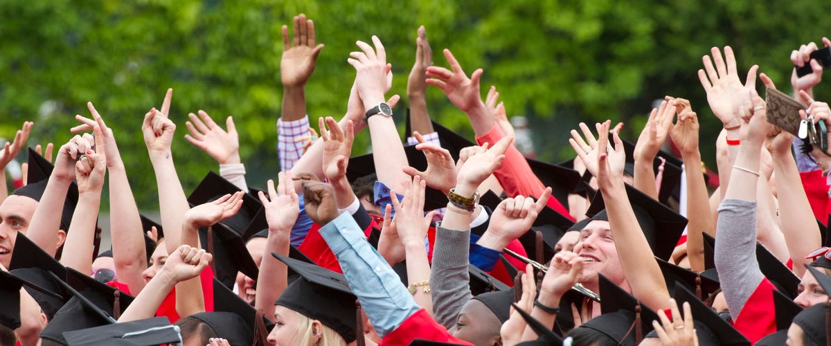 A group of people at graduation with their hands up