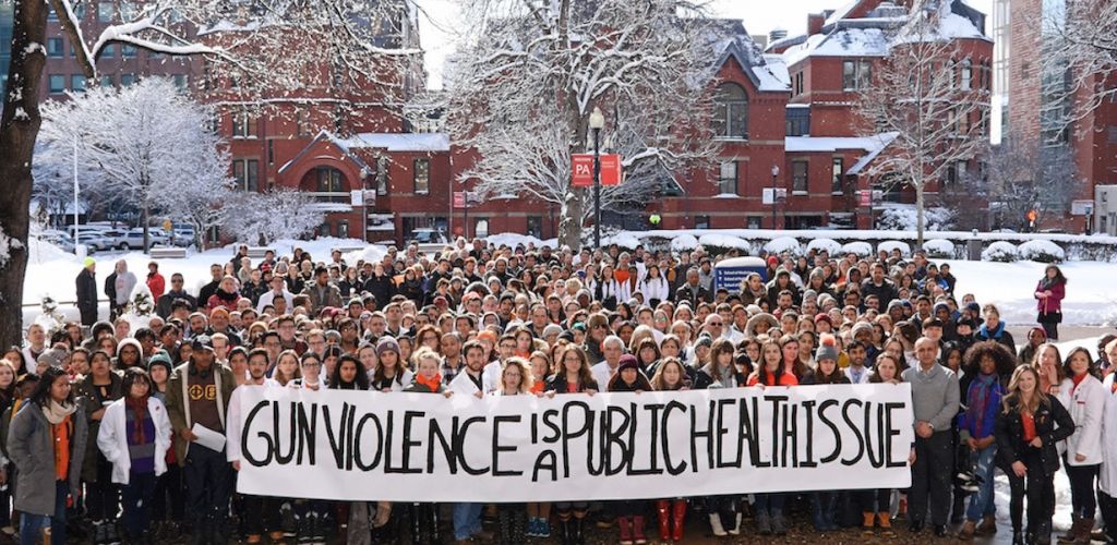 BU Medical Campus walk-out for gun violence; crowd stands in front of SPH's Talbot Building in the snow, holding a banner that reads "Gun VIolence Is a Public Health Issue"