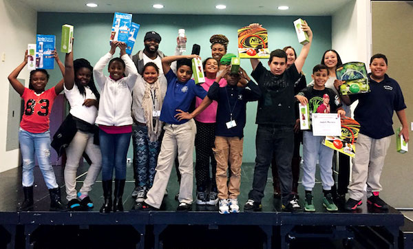 A group of 9-to-12-year-olds pose with water bottles and boxes of water-flavoring.