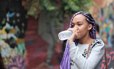 A young Black woman drinking from a water bottle