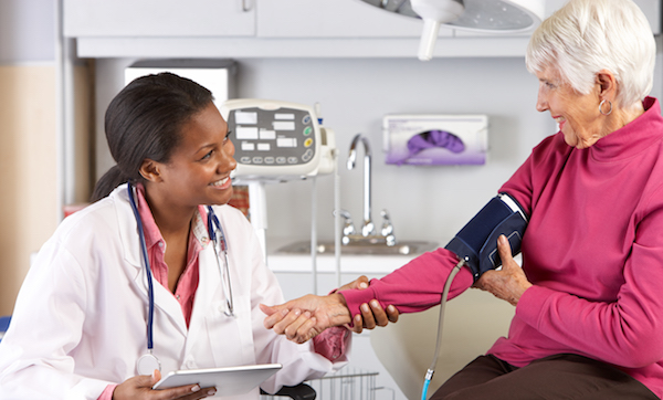 Doctor taking older patient's blood pressure