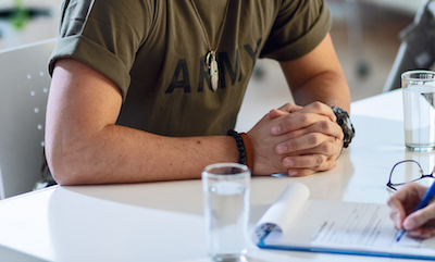 Young sad military officer sitting at doctor's office during his psychotherapy.