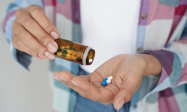 Close-up female hands holding pills and medicine jar