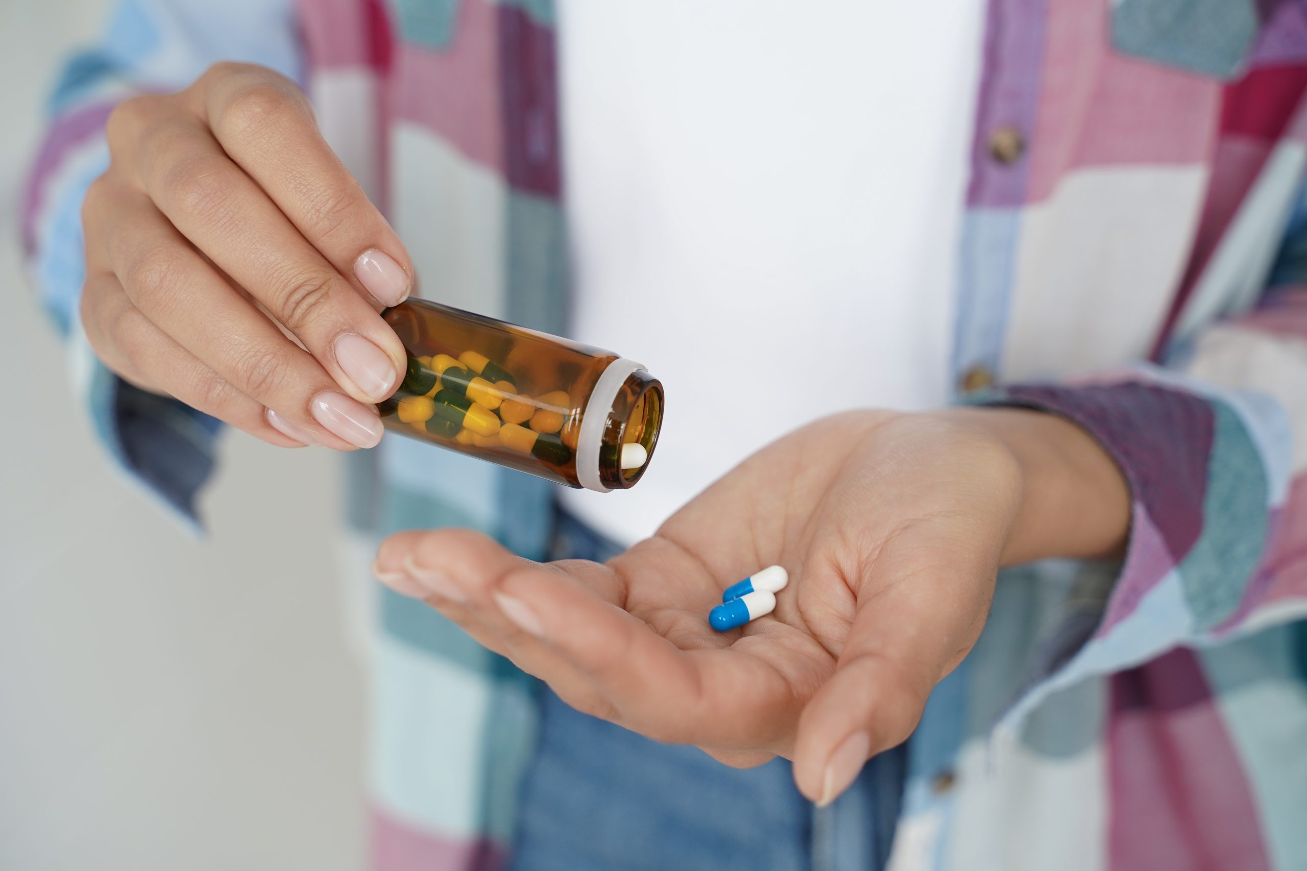 Close-up female hands holding pills and medicine jar