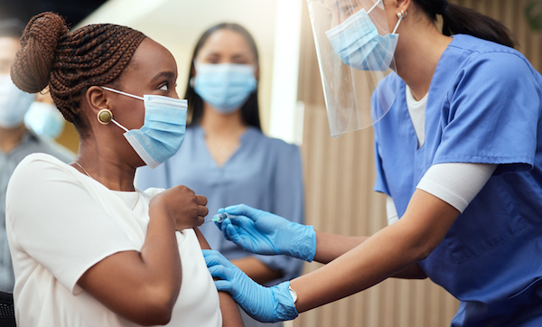 Cropped shot of an young woman getting her covid vaccination from a female nurse in the office