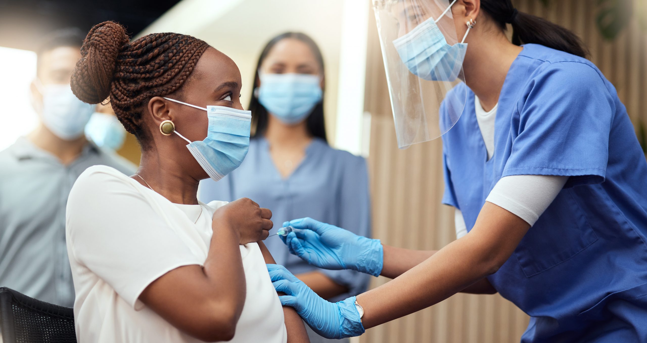 Cropped shot of an young woman getting her covid vaccination from a female nurse in the office