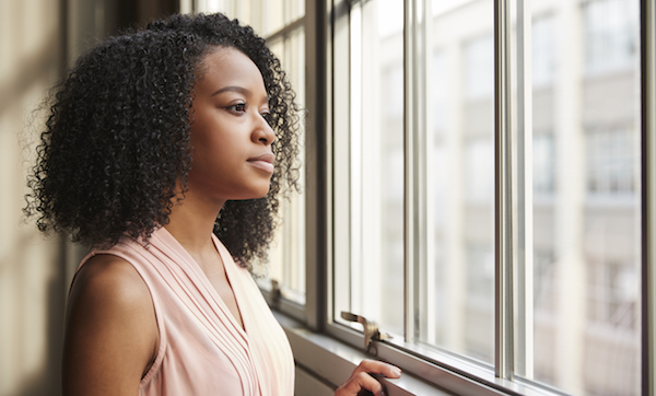 Young black businesswoman looking out of window