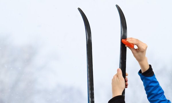 Hands putting wax on skis