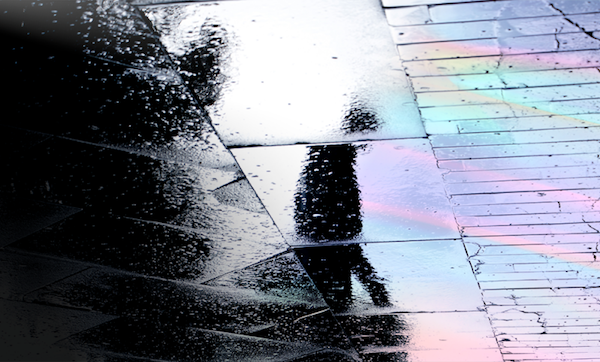 Shadow of a person visible on wet and oily ground