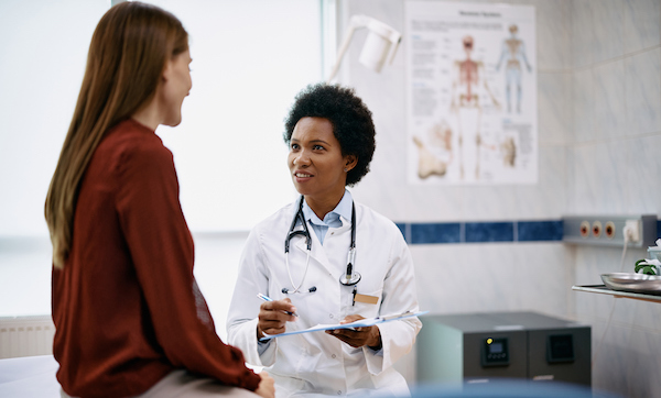 Black female doctor talking to a woman during medical appointment in the hospital.