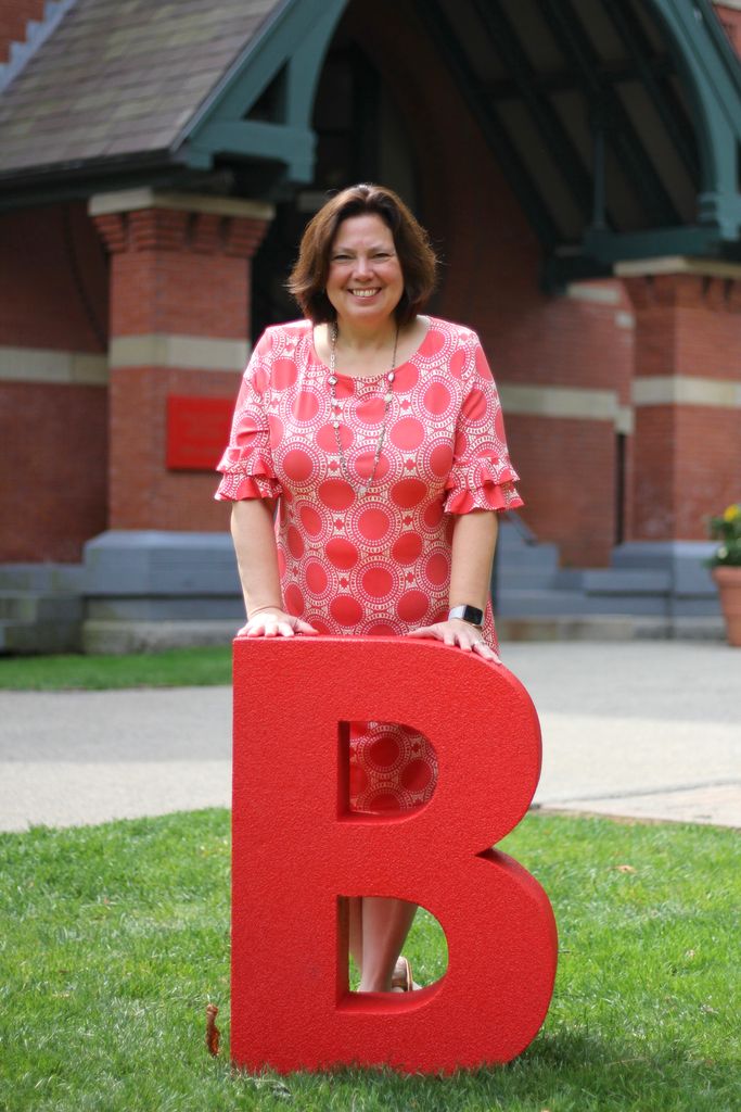 Mary Murphy-Phillips standing behind a large letter B in front of the Talbot Building