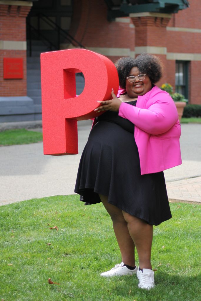 Robyn Volcy-Lee standing in front of the Talbot Building holding a large letter P
