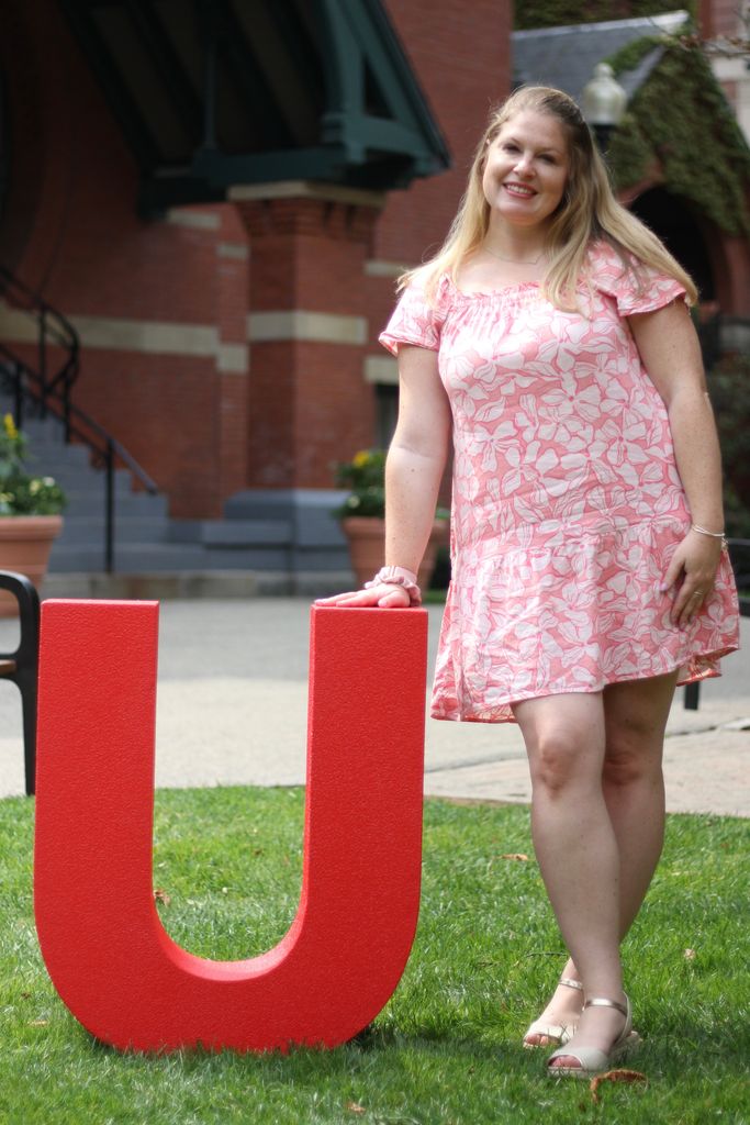 Ashley Leonard standing beside a large letter U in front of the Talbot Building