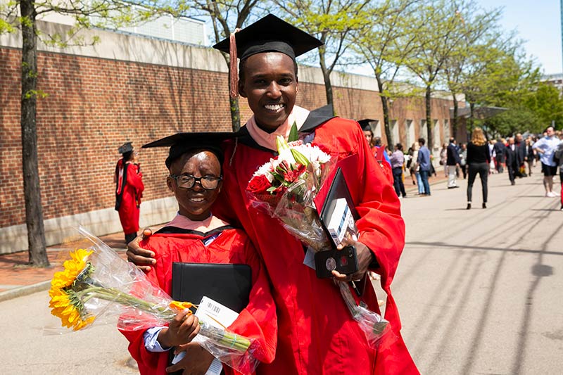 Alex and Leo wearing matching red robes and holding bouquets of flowers at SPH Convocation in May 2019