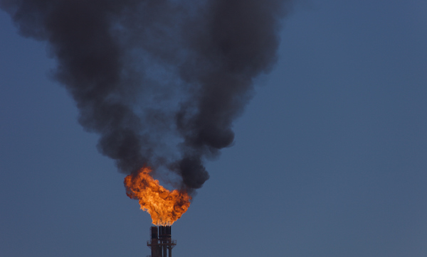 Closeup of gas flare and dense black smoke in the sky