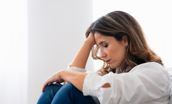 Close-up side view of a lonely woman sitting at home with sad look