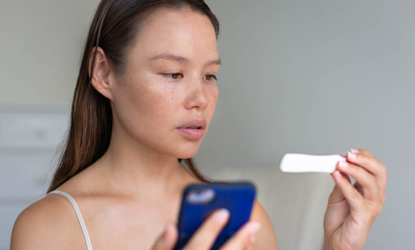 A woman waiting for pregnancy test results, holding her phone.