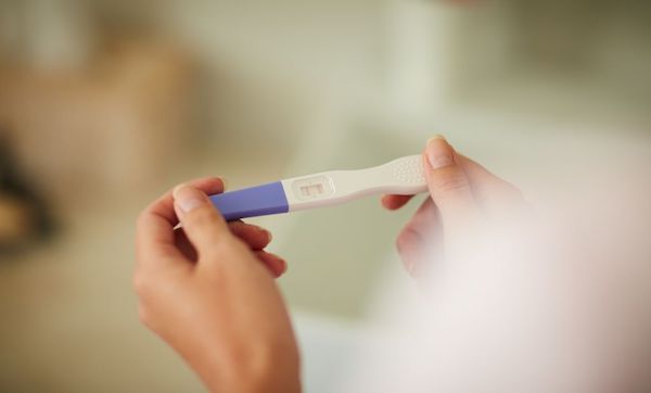 Cropped shot of an unrecognizable woman holding a pregnancy test in the bathroom at home