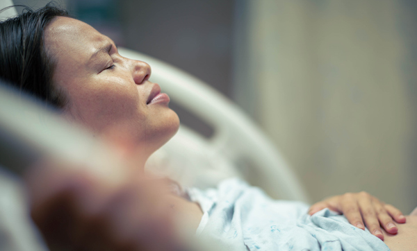 A sick woman patient in bed at the hospital suffering from pain. Contractions and childbirth.