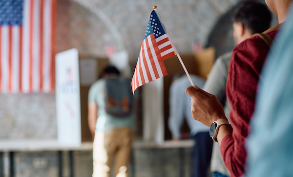 Close up of African American voter with national flag in waiting line during US elections.