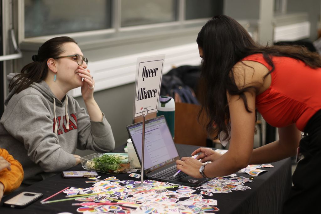 A student signs up for an email list using a laptop at the Queer Alliance table during a student organization fair.