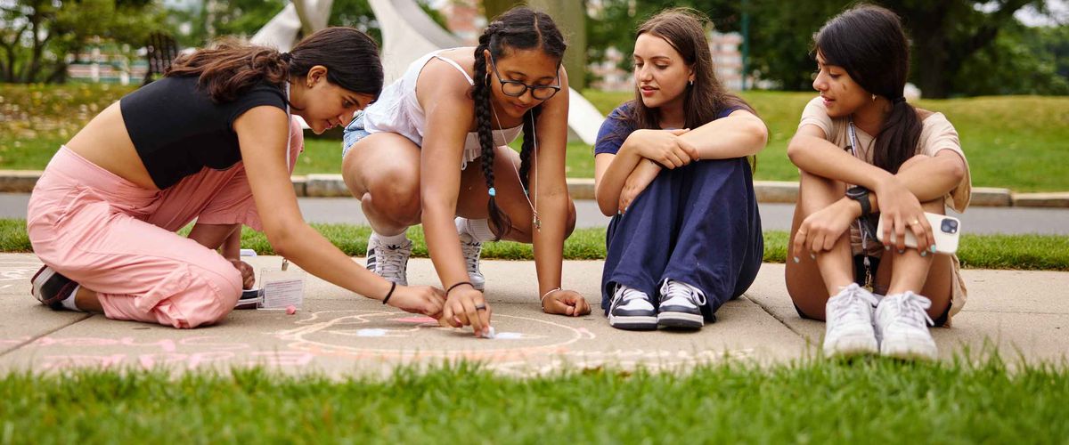 BU Summer Term students drawing on a sidewalk with chalk at the BU Beach
