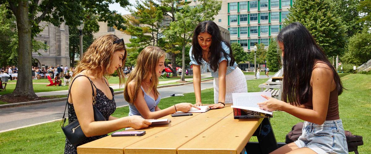 BU Summer Term students read books together outside at a picnic table
