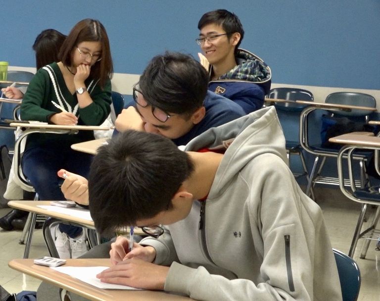 Four students work on handouts in a classroom