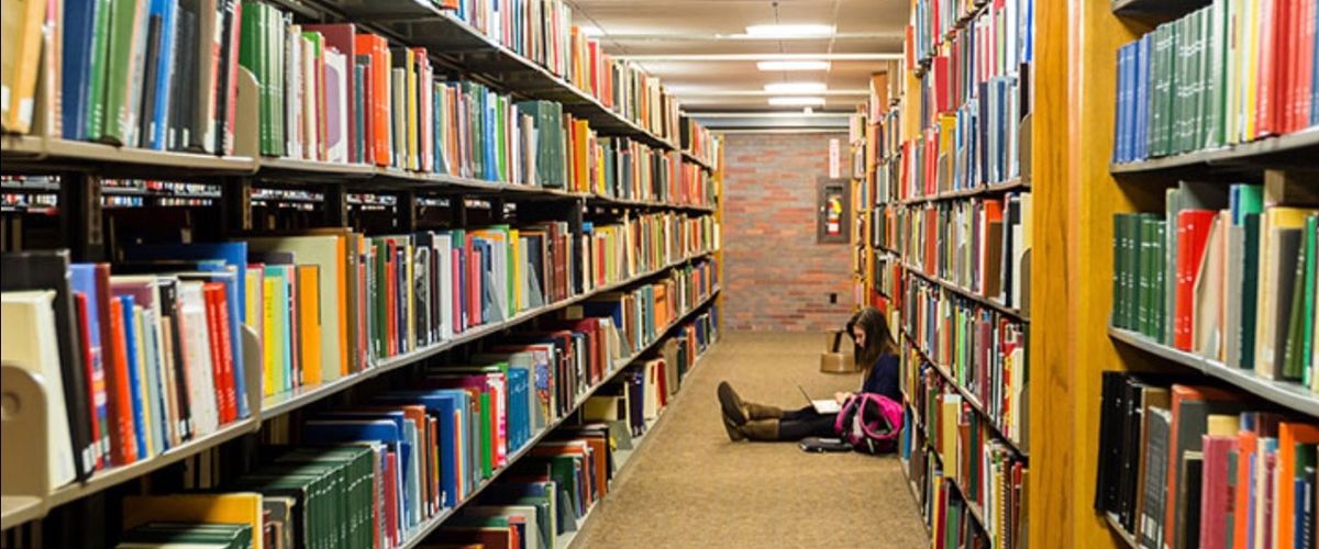A student sitting on the floor in the library