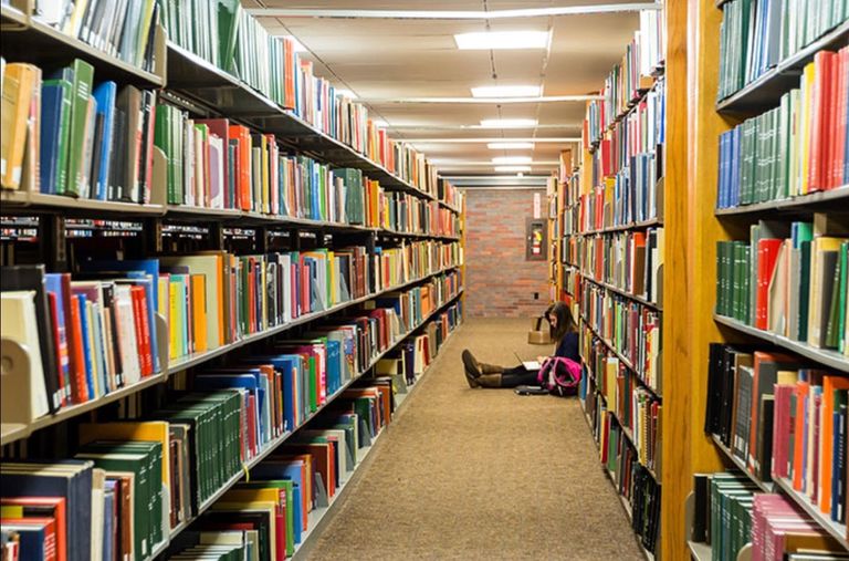 A student sitting on the floor in the library