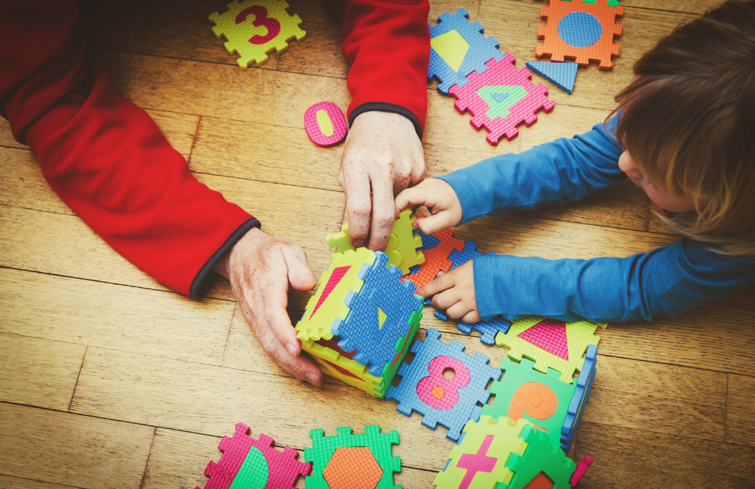 hands of child and adult playing with foam block letters