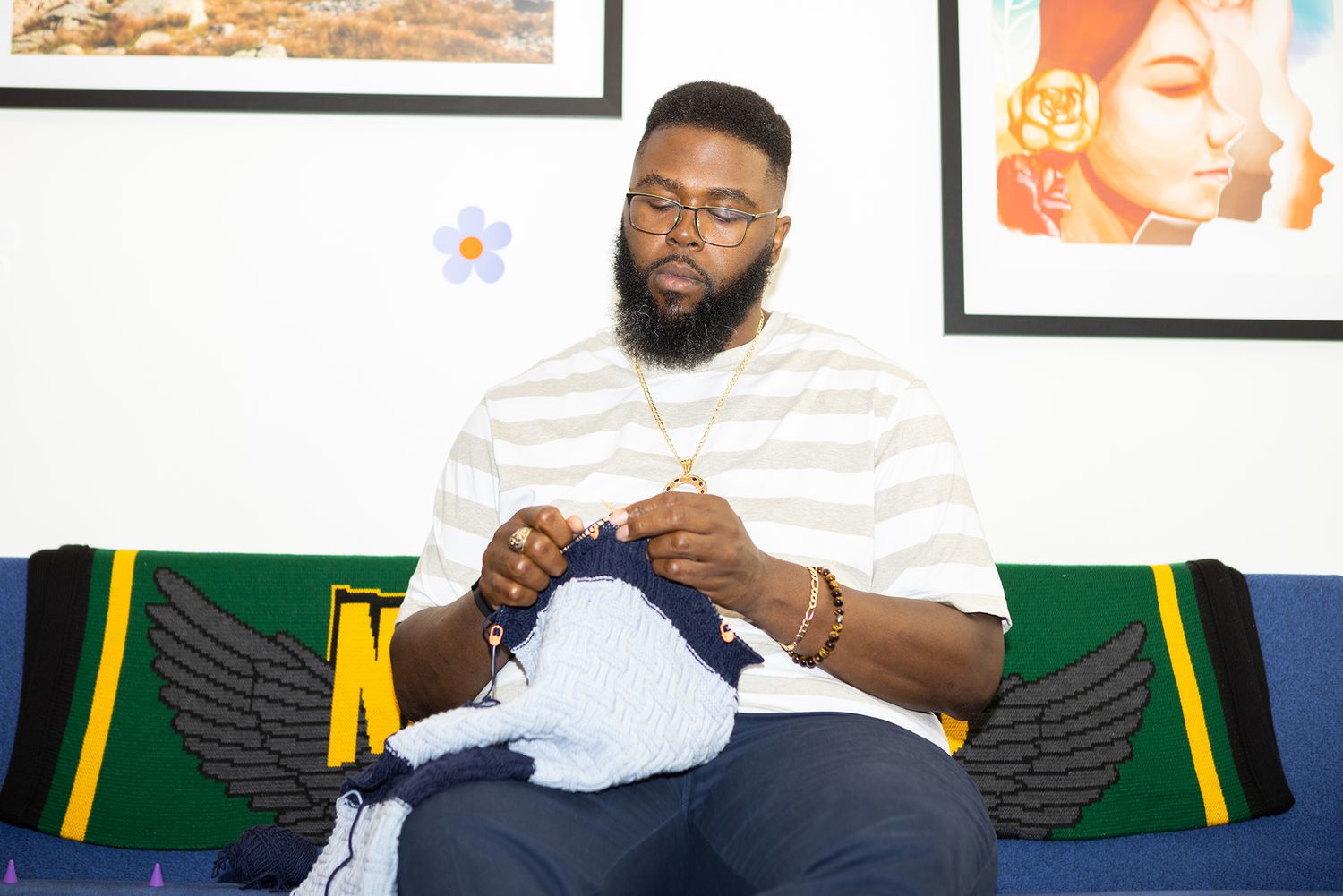 Anthony Jack sitting on a couch knitting 