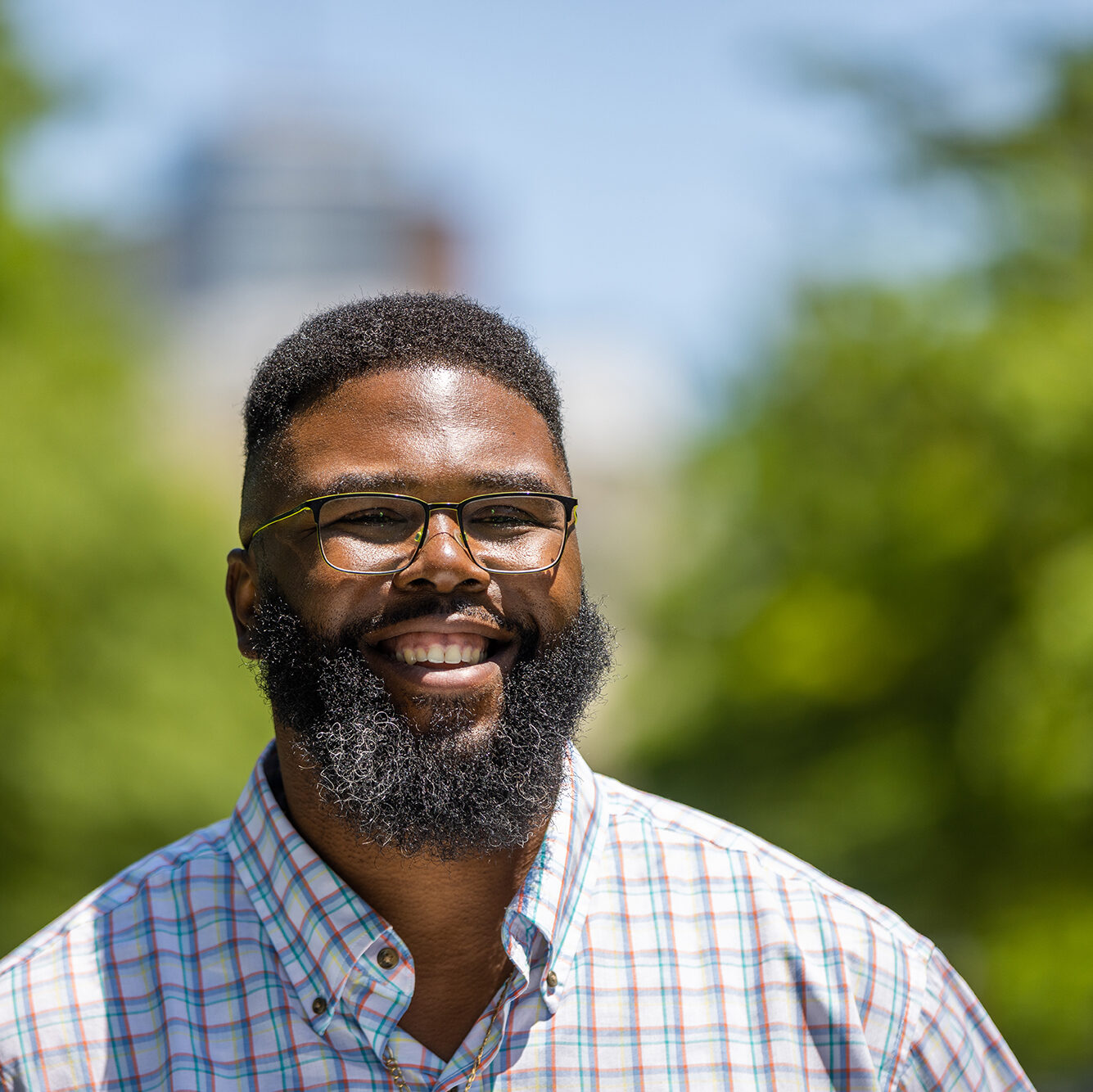 Anthony Jack smiling with blurred green trees in the background