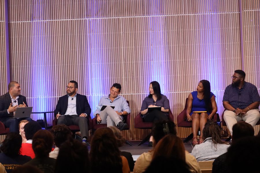 a group of panelist speaking at event on a stage