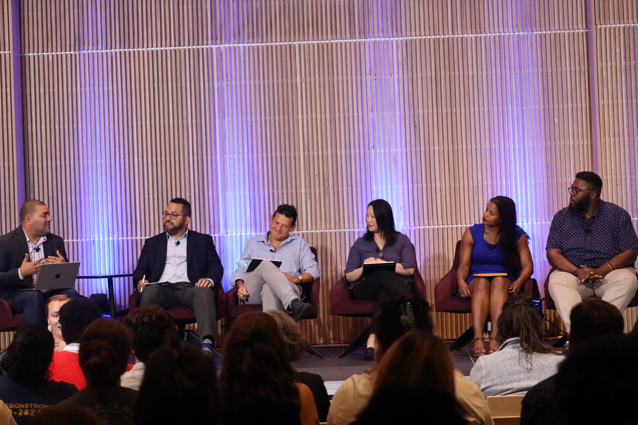 a group of panelist speaking at event on a stage