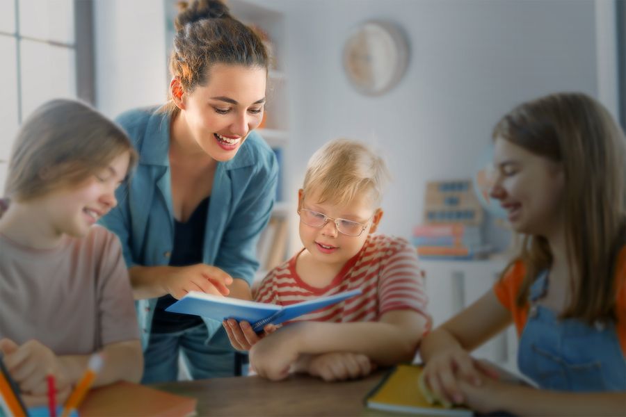 Happy kids and teacher at school. Woman and children are talking in the class.