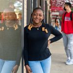 Photo of Brianna leaning against glass window smiling on busy Boston street