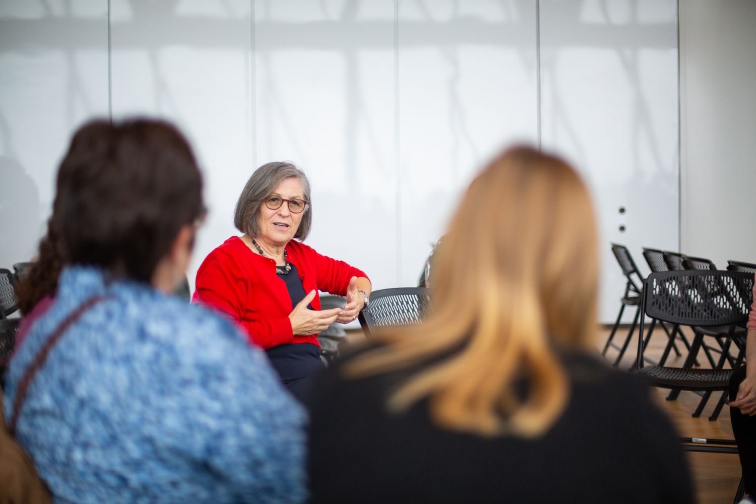 women in red sweater sits speaking with partipants at the curiosity & learning confernece