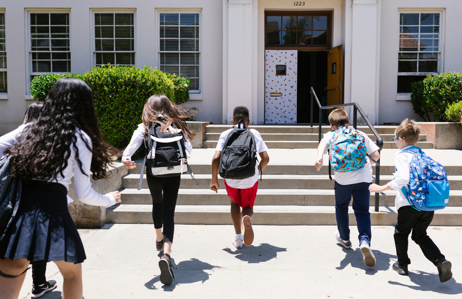 5 middle school ages kids running towards their school