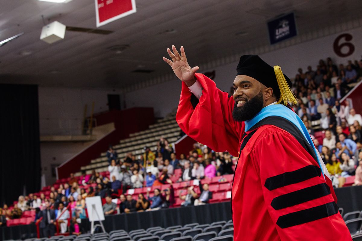 Man with graduation cap on waving to the crowd at graduation