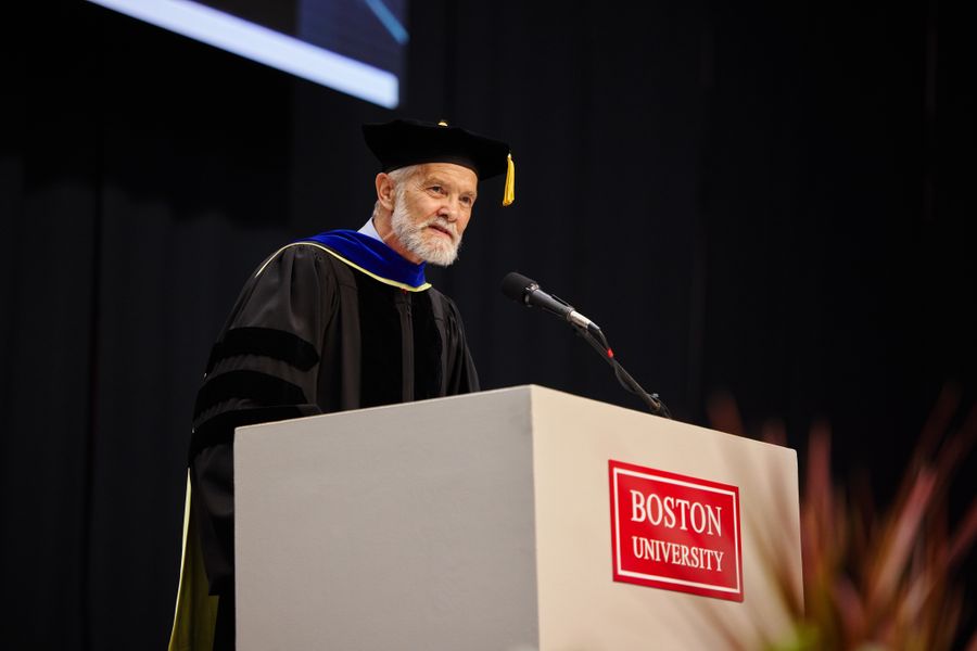 Dean David Chard in full regalia speaking at the podium