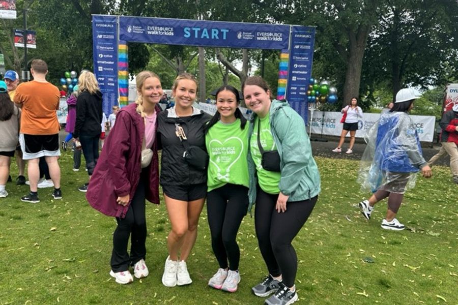 Four young women dressed for exercise pose in front of a sign that says Walk for Kids