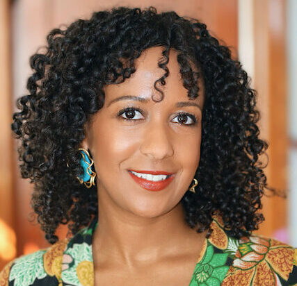 Shows Jalene Tamerat, a woman with curly dark hair wearing a multicolored top