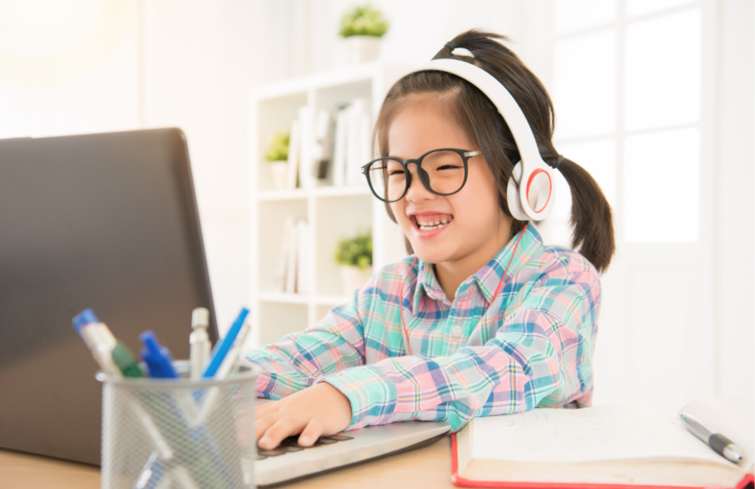 Young girl smiling with headphones on looking at a laptop