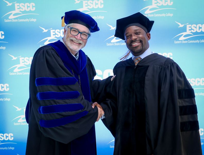 Jim Shaeffer shaking the hand of fellow ESCC community member in regalia