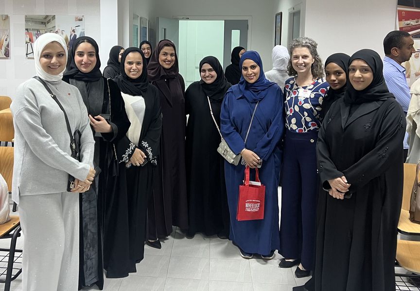 Dean Penny Bishop smiling with a group of students in Bahrain
