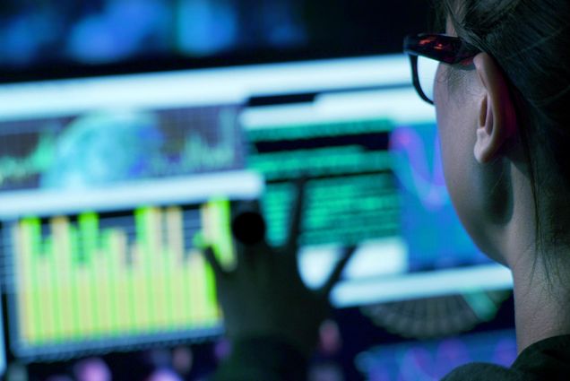 View over the shoulder of a woman working with data on a computer screen.