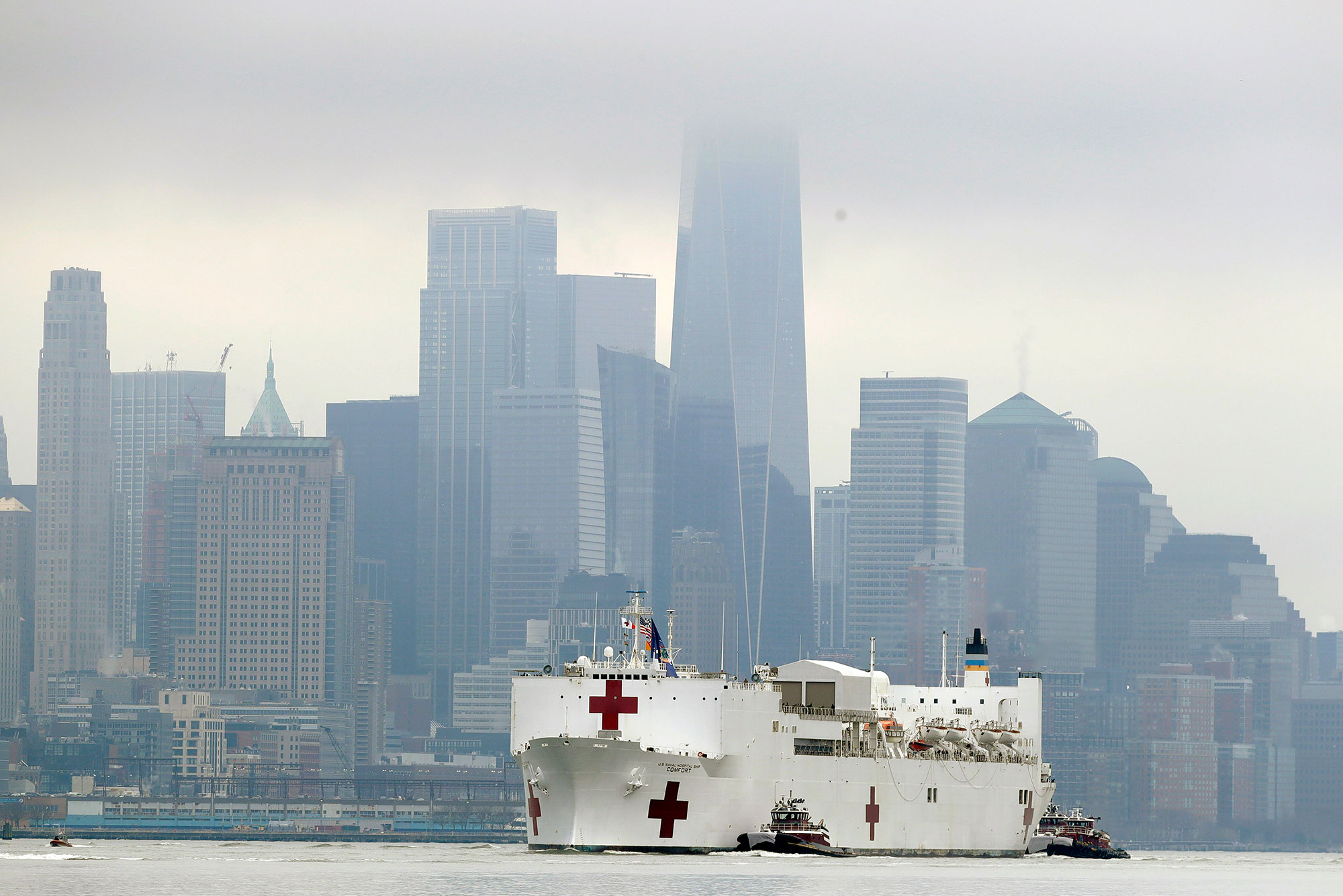 Photo of the Navy hospital ship USNS Comfort passes lower Manhattan on its way to docking in New York, Monday, March 30, 2020, with a foggy Manhattan skyline in the background.