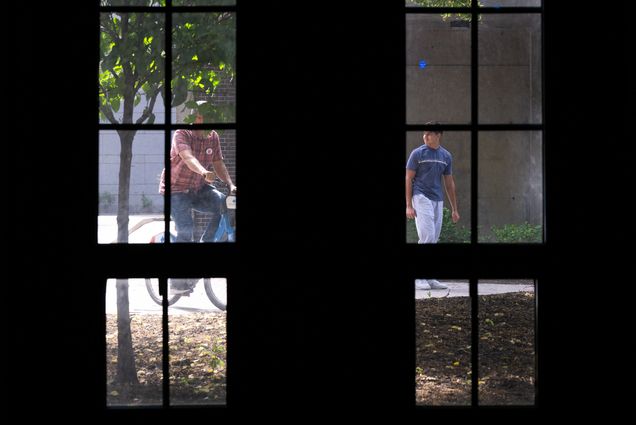Photo: Two men, one on a bike, as viewed from a tall window