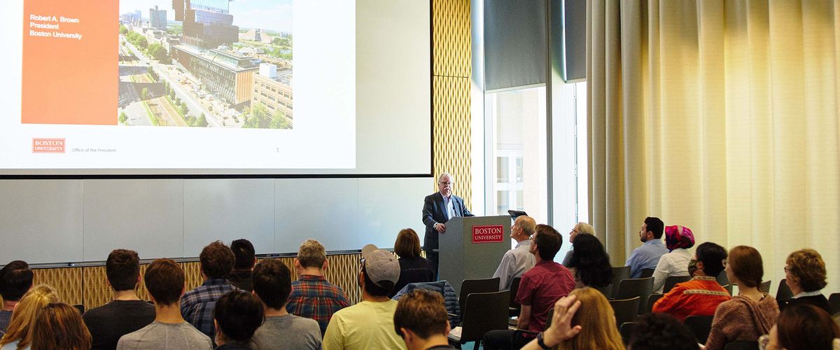 A man behind podium presents to audience